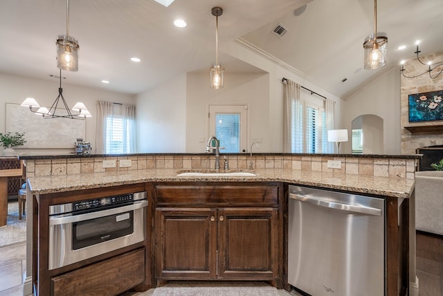 5607 Camino Reale, Midland, TX 79707 - kitchen featuring appliances with stainless steel finishes, a sink, light stone counters, dark brown cabinets, and vaulted ceiling