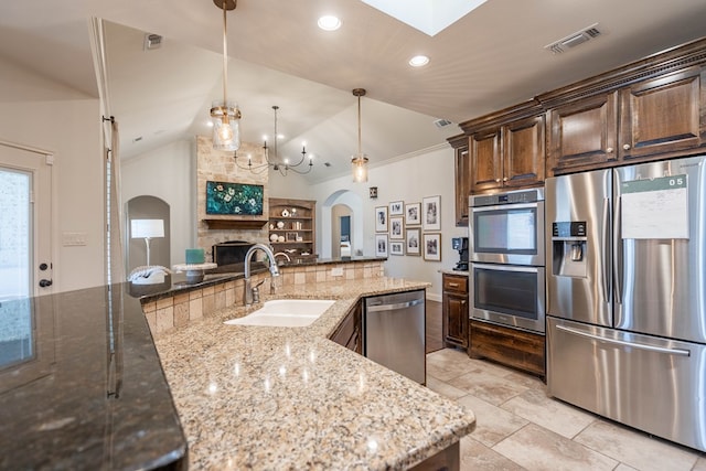 5607 Camino Reale, Midland, TX 79707 - kitchen with appliances with stainless steel finishes, a sink, arched walkways, light stone counters, and vaulted ceiling