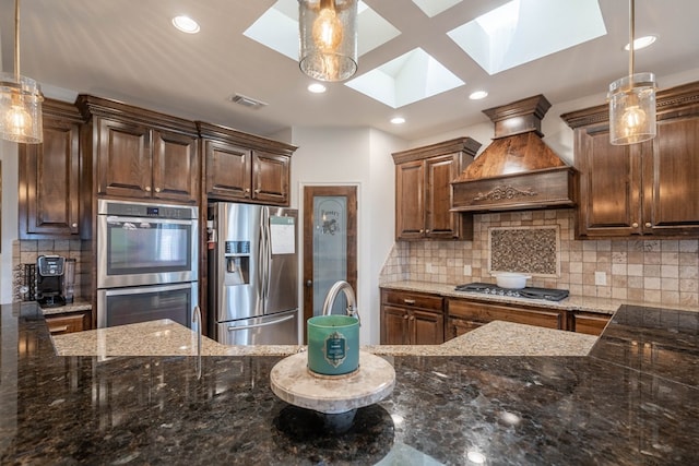 5607 Camino Reale, Midland, TX 79707 - kitchen featuring stainless steel appliances, a skylight, custom exhaust hood, dark stone counters, and recessed lighting