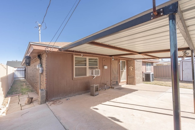 rear view of house featuring brick siding, a patio area, a fenced backyard, and central AC