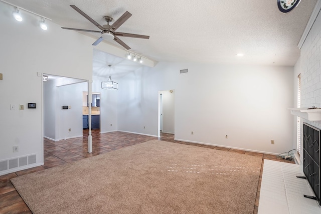 unfurnished living room featuring a brick fireplace, ceiling fan with notable chandelier, visible vents, and a textured ceiling