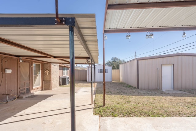 view of yard featuring fence, a shed, central air condition unit, an outdoor structure, and a patio