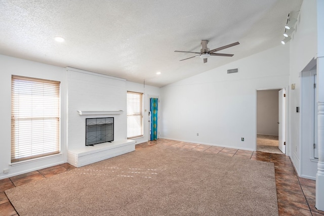 unfurnished living room featuring lofted ceiling, a brick fireplace, a healthy amount of sunlight, and visible vents