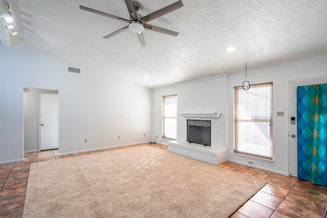 unfurnished living room with visible vents, a brick fireplace, ceiling fan, vaulted ceiling, and a textured ceiling