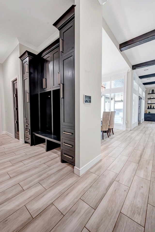 mudroom featuring beamed ceiling, wood tiled floor, and baseboards