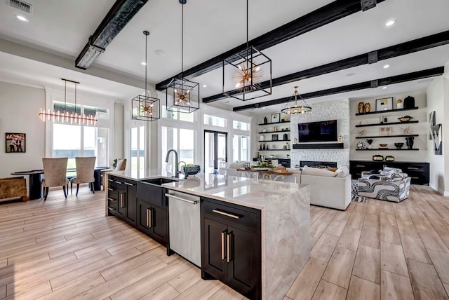 kitchen featuring a sink, light wood-style floors, dishwasher, beamed ceiling, and visible vents