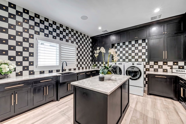 kitchen with visible vents, decorative backsplash, a sink, and washer and dryer