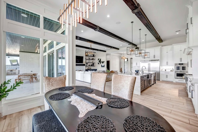 dining area featuring an inviting chandelier, beam ceiling, and light wood finished floors