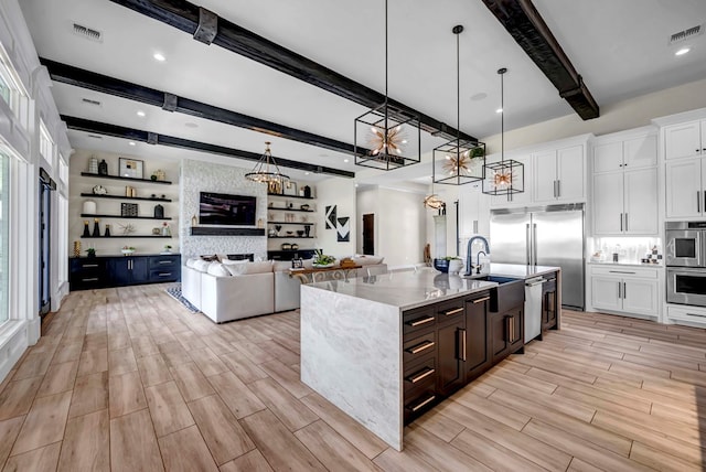 kitchen featuring open floor plan, white cabinetry, beamed ceiling, and visible vents