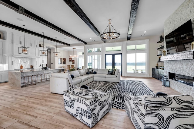 living area with a fireplace, beam ceiling, and an inviting chandelier