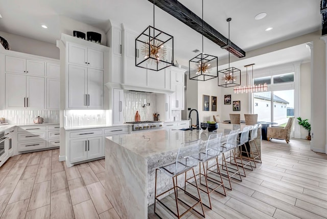 kitchen with backsplash, a spacious island, white cabinets, and an inviting chandelier