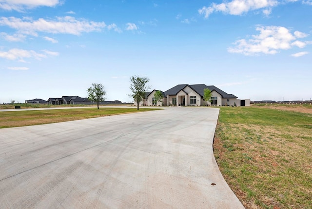 view of front of house featuring a front lawn and curved driveway