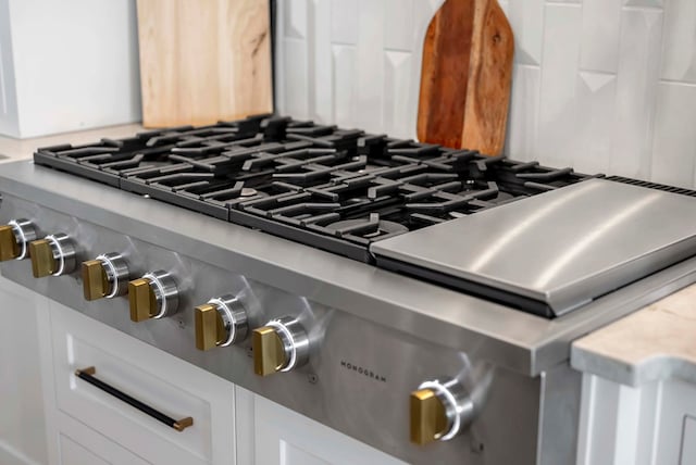 interior details with white cabinetry, stove, and light countertops