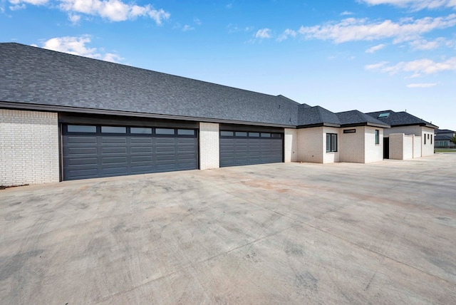 view of front of home featuring brick siding, an attached garage, driveway, and a shingled roof
