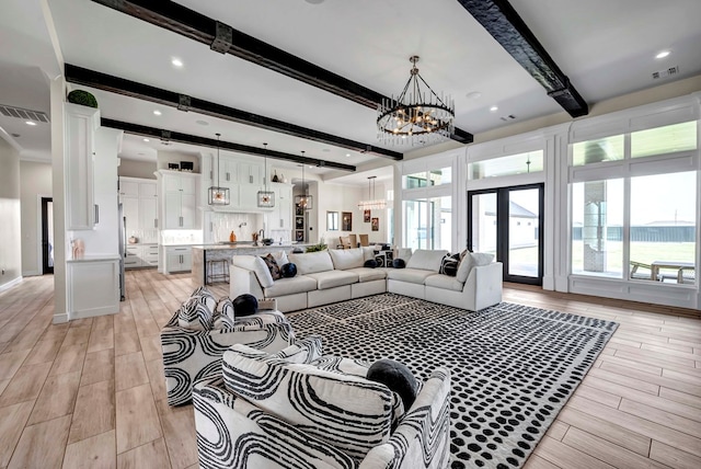 living room with wood finish floors, an inviting chandelier, beam ceiling, and visible vents