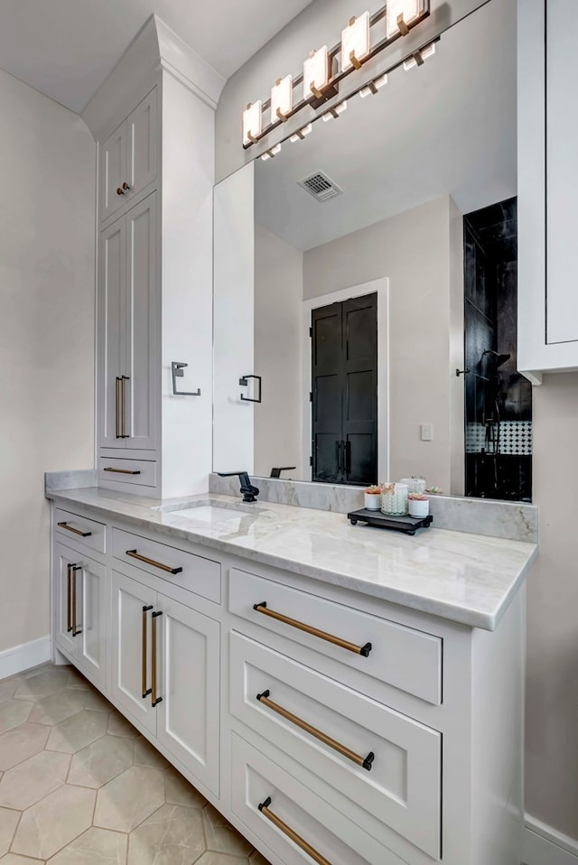 bathroom featuring visible vents, baseboards, vanity, tile patterned flooring, and tiled shower