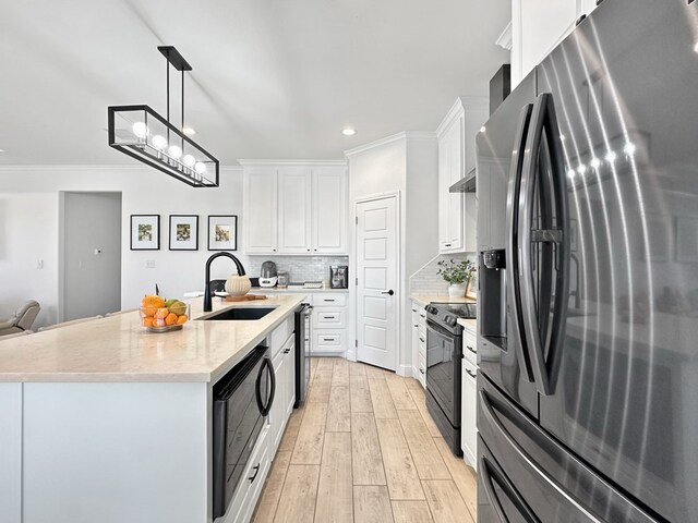 kitchen with white cabinetry, sink, a center island with sink, black appliances, and light wood-type flooring