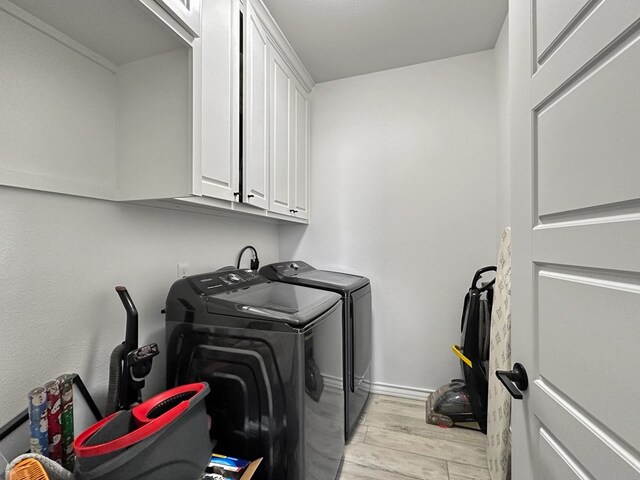 laundry area with washer and clothes dryer, light hardwood / wood-style floors, and cabinets