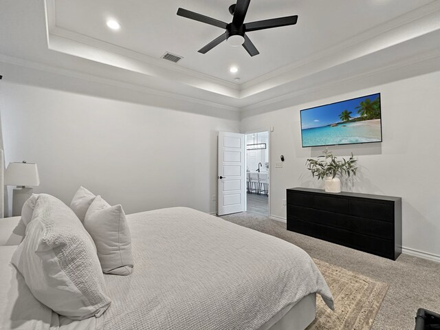 carpeted bedroom featuring ceiling fan, crown molding, and a tray ceiling