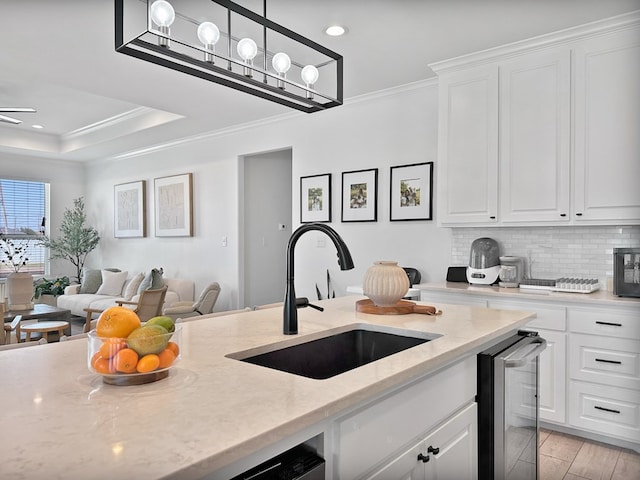 kitchen featuring light wood-type flooring, light stone counters, crown molding, sink, and white cabinets