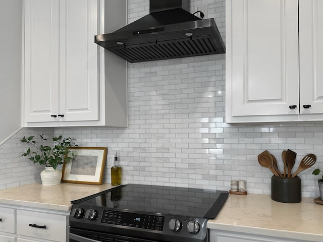 kitchen with tasteful backsplash, range with electric cooktop, white cabinets, and custom range hood