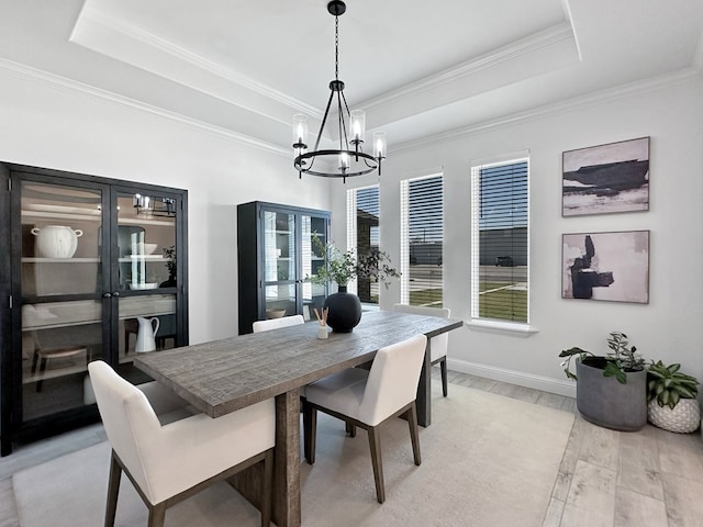 dining room with light hardwood / wood-style floors, a raised ceiling, and a healthy amount of sunlight