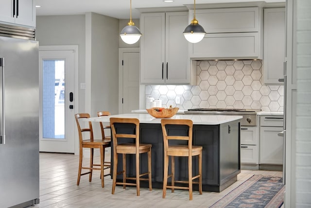 kitchen featuring high end refrigerator, a breakfast bar area, a center island, light countertops, and backsplash