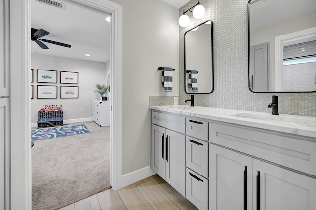 bathroom with double vanity, ceiling fan, a sink, and wood finished floors