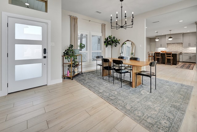 dining space with light wood finished floors, recessed lighting, visible vents, and an inviting chandelier