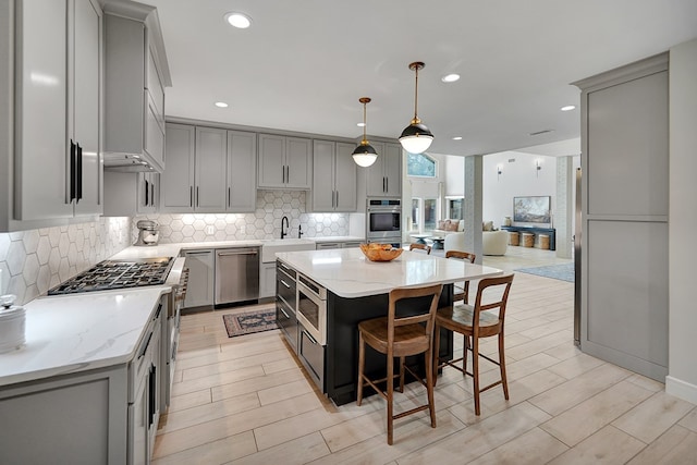 kitchen with stainless steel appliances, wood finish floors, backsplash, and gray cabinetry