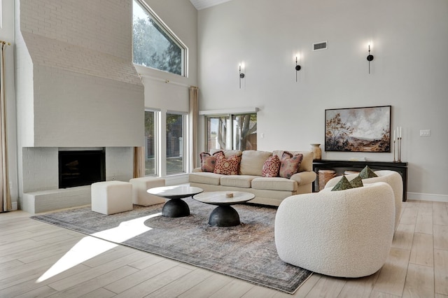 living room featuring a fireplace, wood finished floors, visible vents, and a healthy amount of sunlight