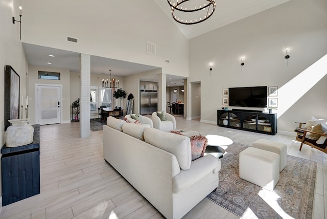 living area with baseboards, light wood finished floors, visible vents, and an inviting chandelier