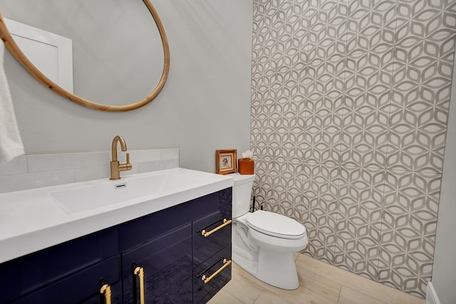 bathroom with toilet, a shower, wood finished floors, and vanity