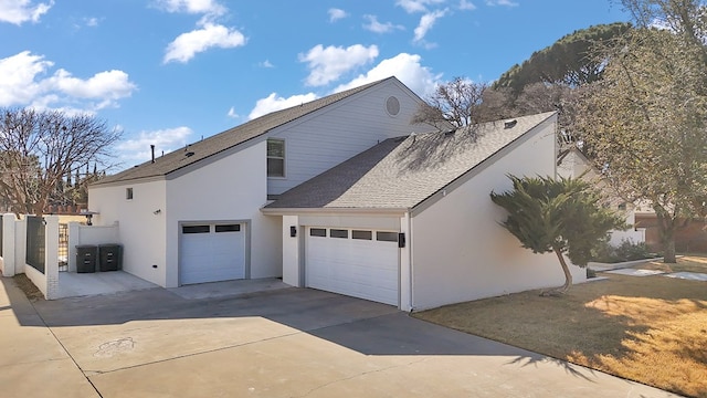 view of home's exterior with a shingled roof, concrete driveway, an attached garage, and stucco siding