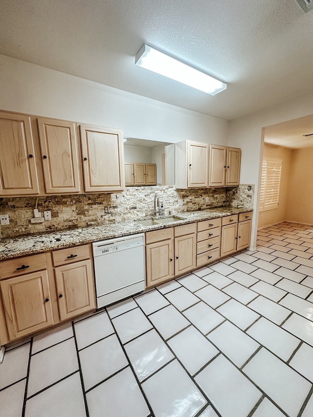 kitchen with light brown cabinetry, sink, light stone counters, dishwasher, and backsplash