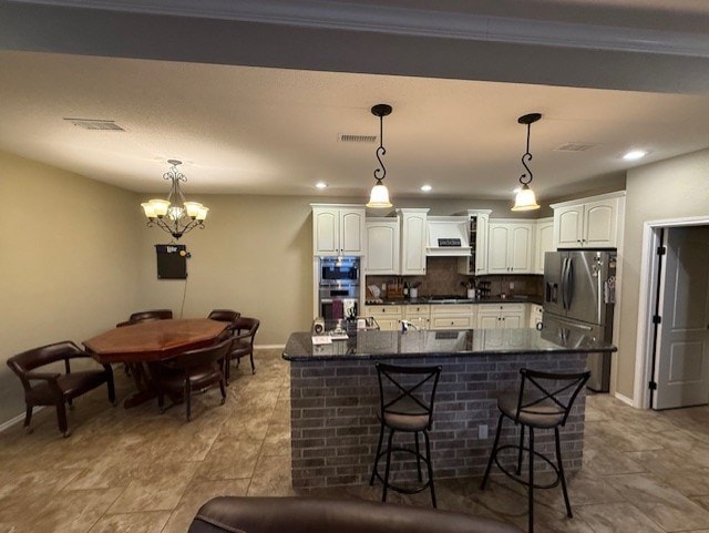 kitchen featuring visible vents, dark countertops, white cabinetry, a chandelier, and stainless steel appliances