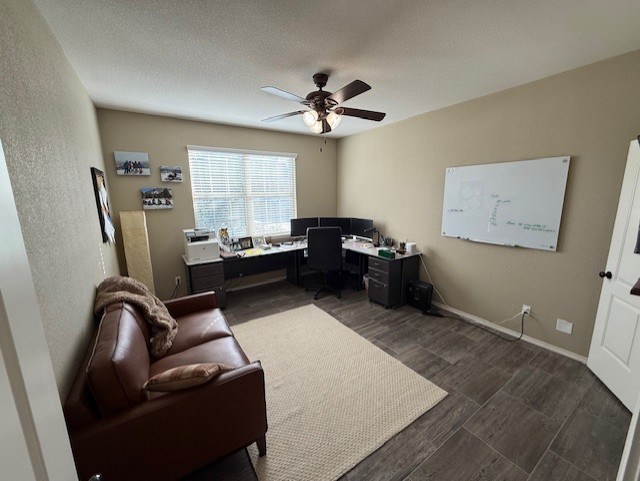office space with baseboards, ceiling fan, a textured ceiling, and dark wood-type flooring