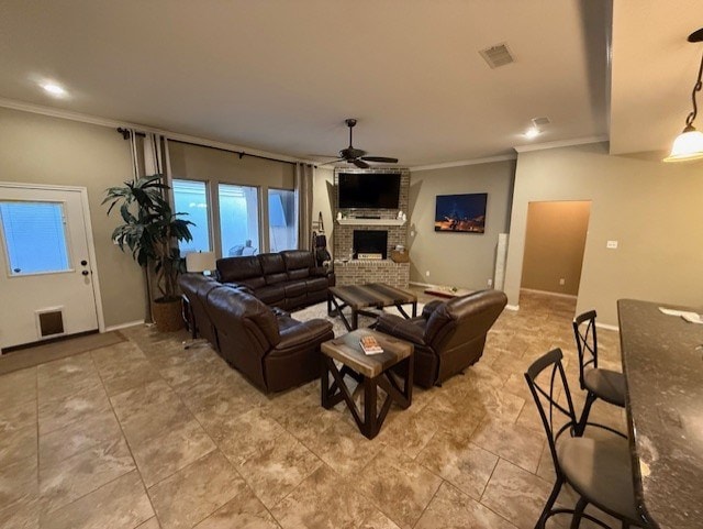 living room with ceiling fan, visible vents, a brick fireplace, baseboards, and ornamental molding