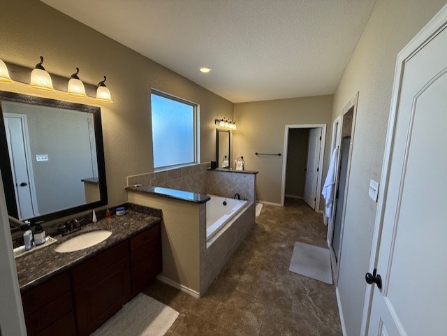 bathroom featuring vanity, a garden tub, and a textured ceiling