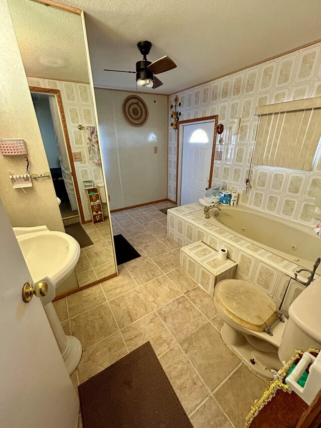 bathroom featuring tile patterned floors, sink, ceiling fan, a textured ceiling, and a tub to relax in