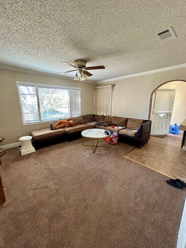 unfurnished living room with ceiling fan, carpet floors, a textured ceiling, and ornamental molding