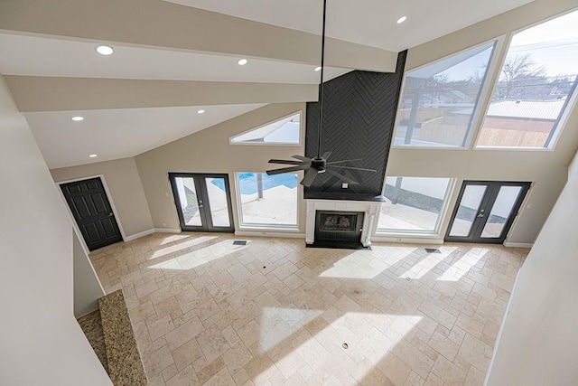 unfurnished living room featuring beam ceiling, high vaulted ceiling, french doors, and ceiling fan