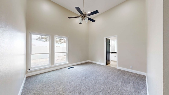 spare room with ceiling fan, light carpet, and high vaulted ceiling