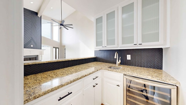 kitchen with wine cooler, white cabinetry, tasteful backsplash, and light stone countertops