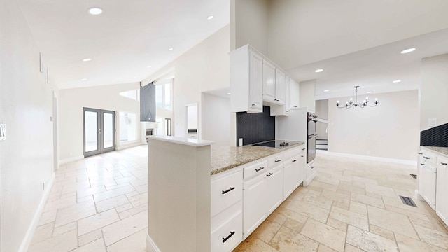 kitchen featuring light stone counters, black electric stovetop, high vaulted ceiling, and white cabinets