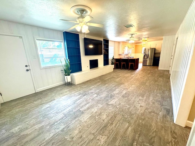 909 Douglas Ave, Midland, TX 79701 - unfurnished living room with ceiling fan, a textured ceiling, wood finished floors, and a fireplace