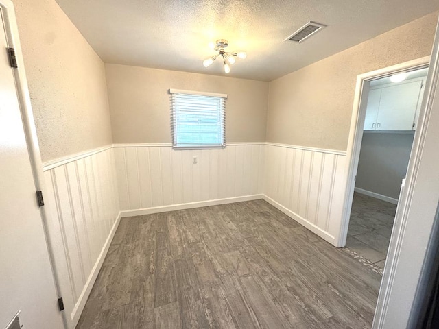 909 Douglas Ave, Midland, TX 79701 - unfurnished room with wainscoting, wood finished floors, a textured ceiling, and a chandelier