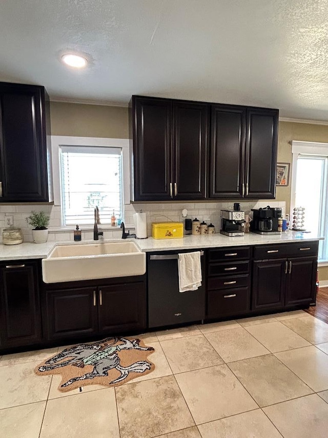 kitchen featuring light tile patterned floors, dark cabinets, dishwasher, and a sink