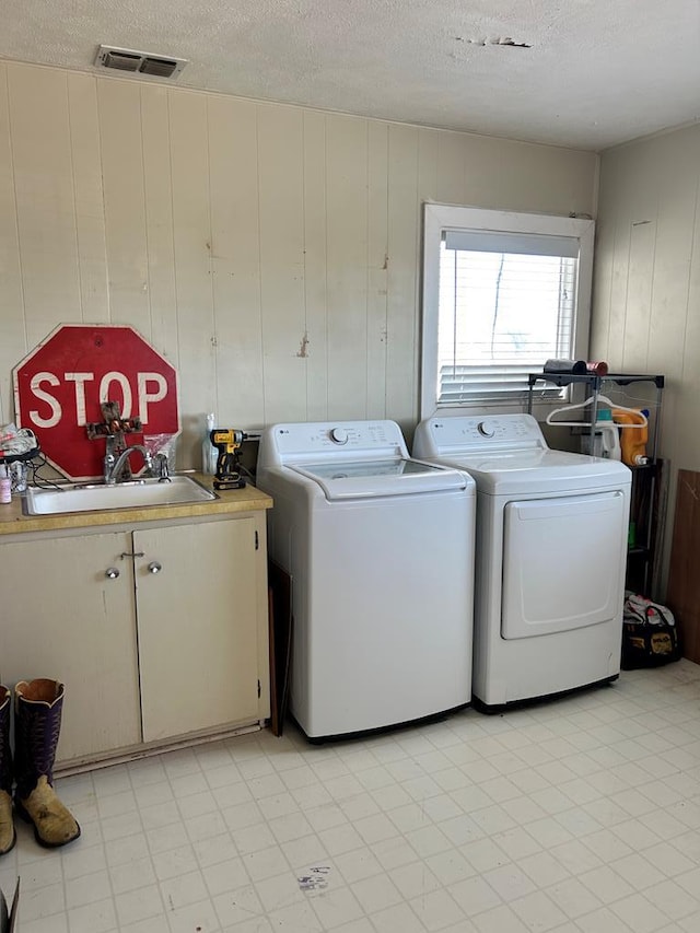 washroom with visible vents, washer and clothes dryer, cabinet space, a textured ceiling, and a sink