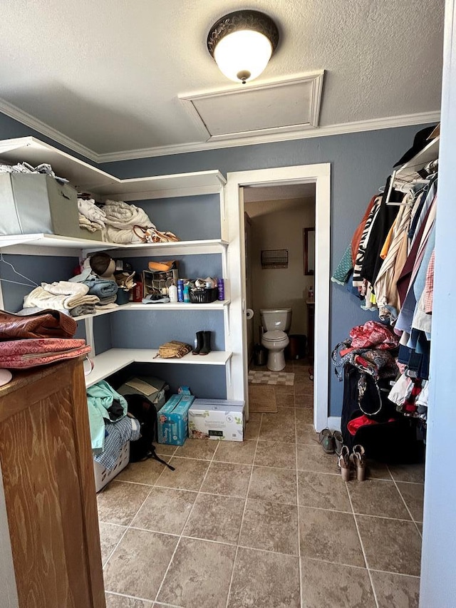 walk in closet featuring tile patterned floors and attic access